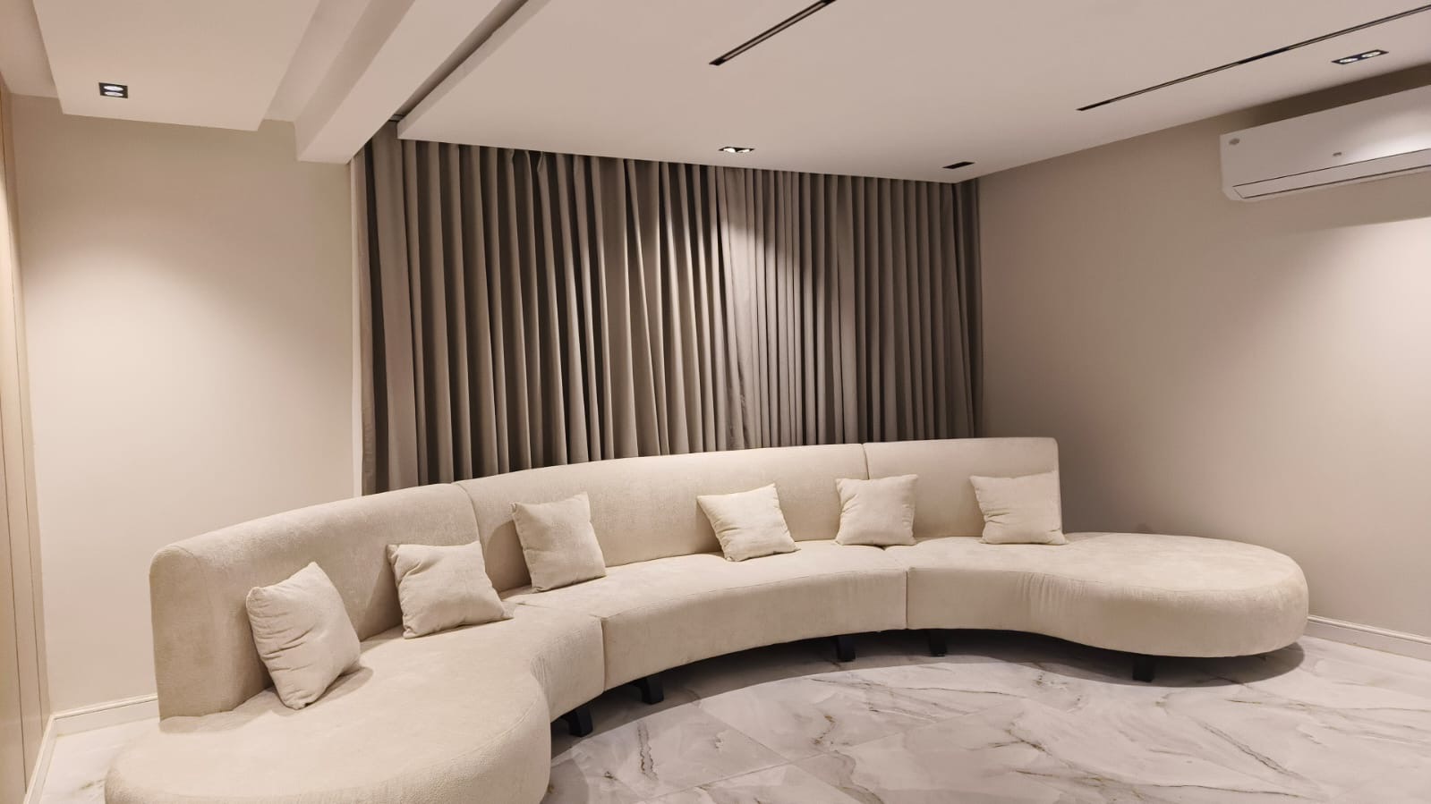 كنبة منحنية طويلة داخل غرفة عائلة بستائر منسقة من Huge Home